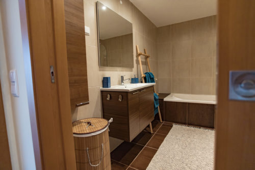 Blick ins Bad mit Spiegel und Waschbecken und Badewanne