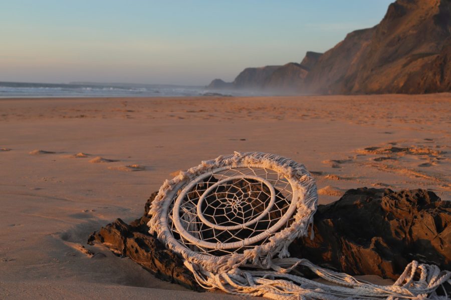 Traumfänger liegt am Strand auf einem Stein im Hintergrund hohe Steilküste und Meer