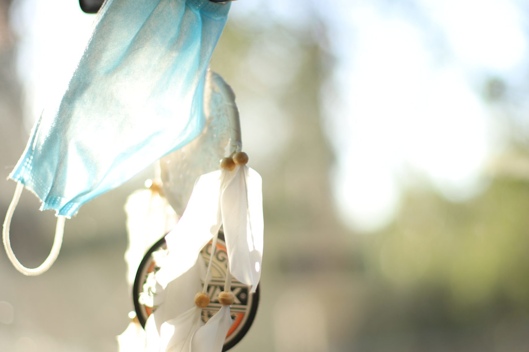 Mundschutz und Traumfänger hängen am Rückspiegel in Auto