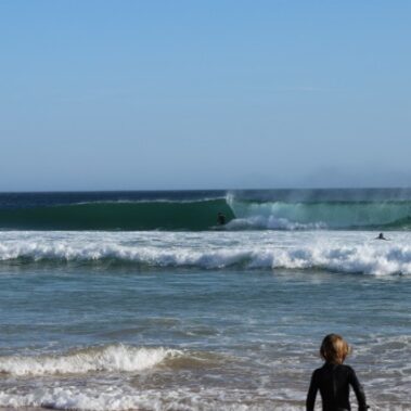 Surfer in Welle am Praia do Zavial
