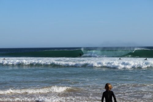 Surfer in Welle am Praia do Zavial