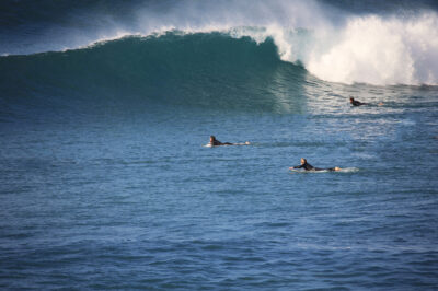 Surfer paddeln gegen eine Welle die bricht